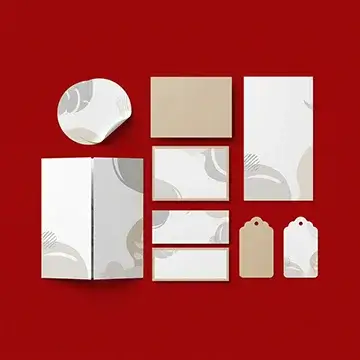 Custom marketing materials such as branded stickers, business cards, hang tags, and brochures on a red background.