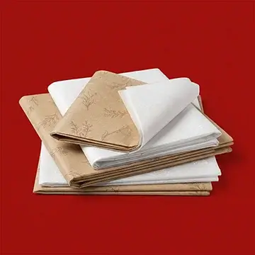 Stack of custom white and kraft tissue papers with floral patterns for gift wrapping and product packaging.